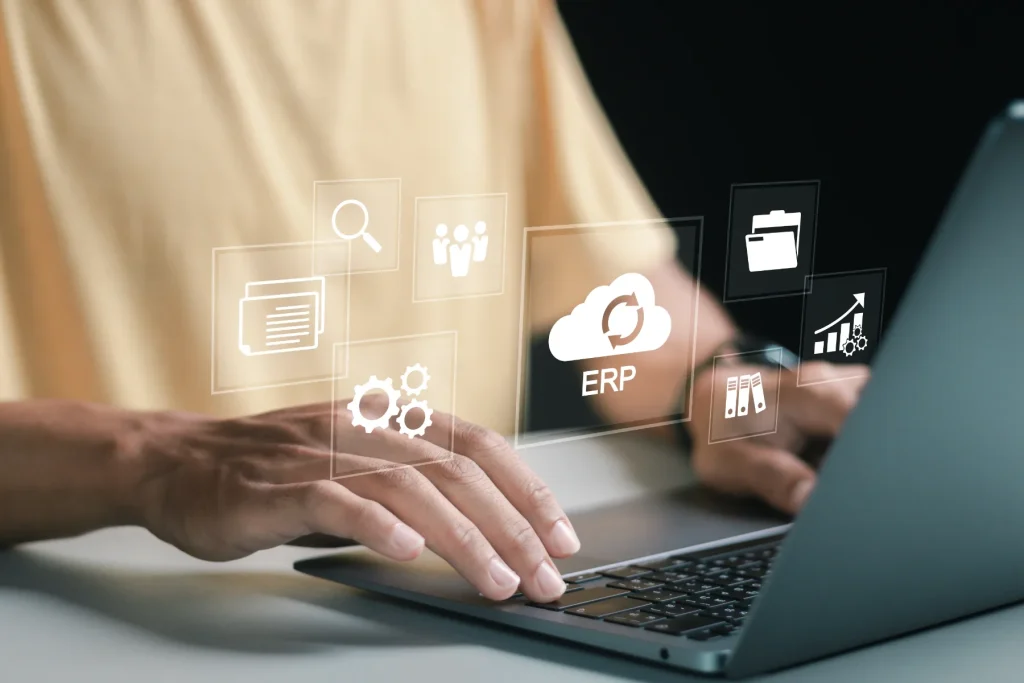 Persona usando una laptop con iconos digitales flotantes de ERP y herramientas empresariales